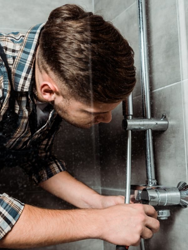 installer touching metallic pipe in bathroom