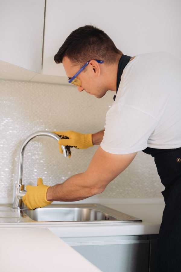 Maintenance man installing plumbing equipment in the kitchen