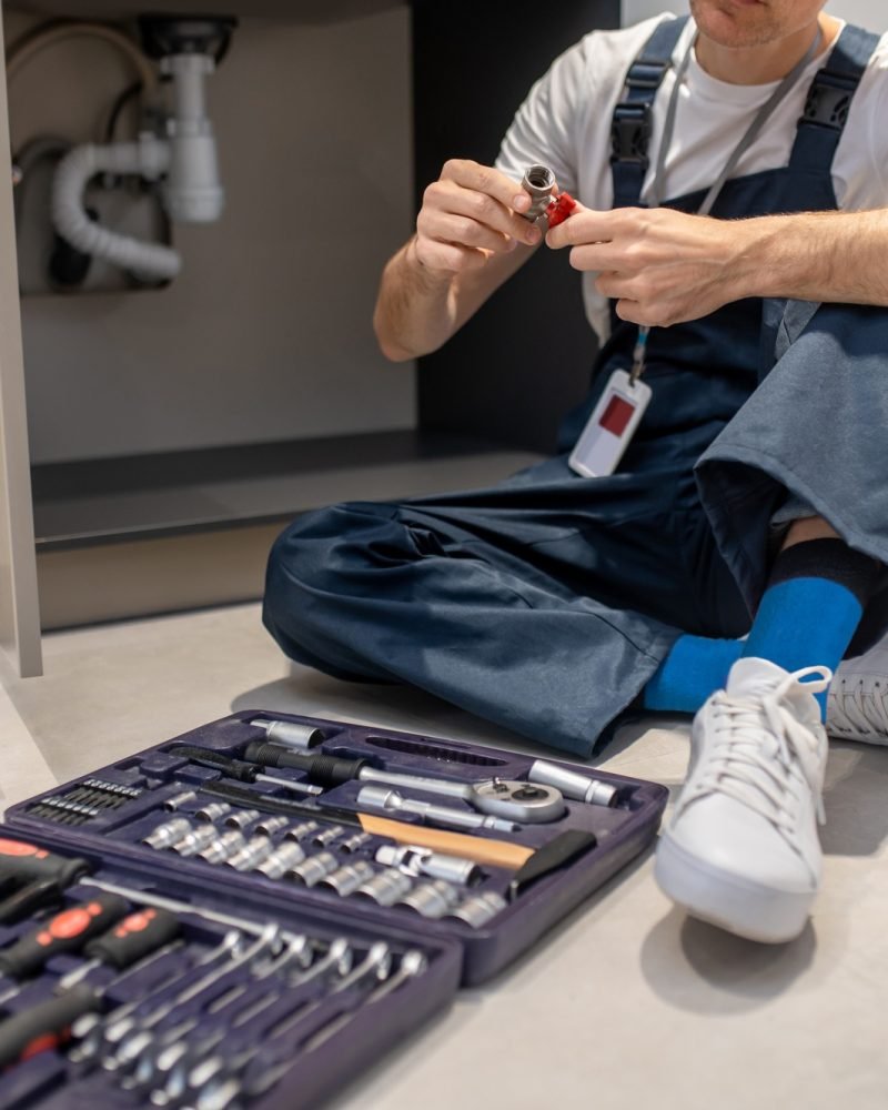 Man sitting on floor with plumbing detail in hands